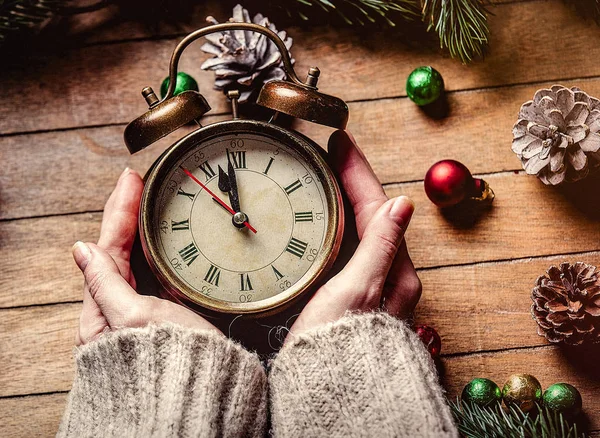 Manos femeninas sosteniendo reloj despertador clásico de Navidad — Foto de Stock