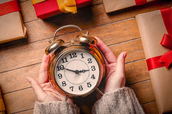 Mulher mãos segurando despertador com presentes de Natal — Fotografia de Stock