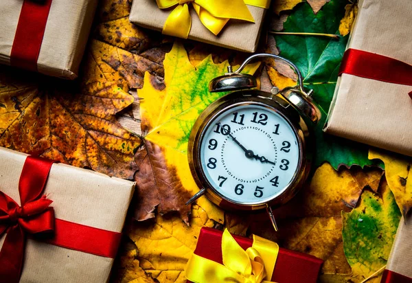 Vintage alarm clock and maple leaves with Holiday gifts — Stock Photo, Image