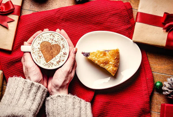 Manos femeninas sosteniendo pastel de Navidad y taza de café — Foto de Stock