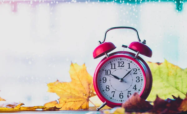 Reloj despertador retro y hojas de arce con gotas de lluvia — Foto de Stock