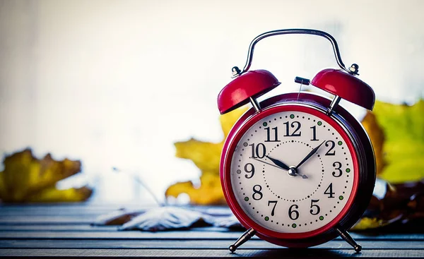 Retro alarm clock and maple leaves with rain drops — Stock Photo, Image