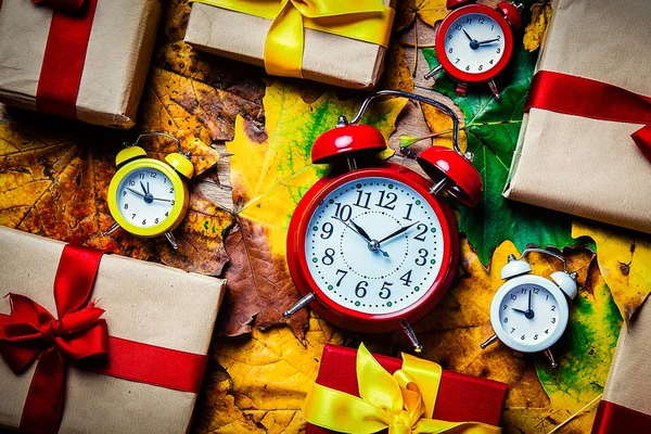 Vintage alarm clocks and maple leaves with Holiday gifts — Stock Photo, Image