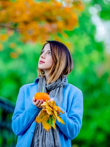 妇女拿着黄色枫树叶子和南瓜在 autum 公园 — 图库照片