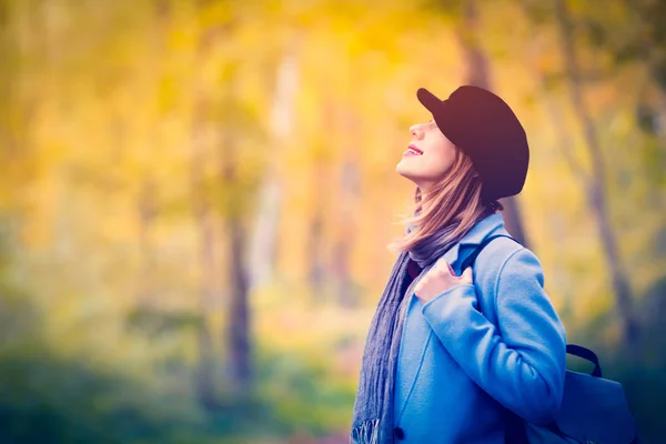 Žena v modrém kabátě a batoh na oddech v podzimní park — Stock fotografie