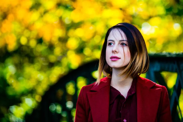 Žena v červeném kabátě si odpočinout v podzimní park — Stock fotografie