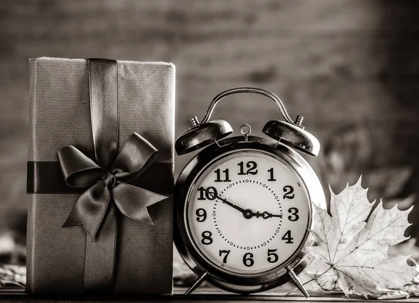 Vintage alarm clock and maple tree leaves with gift box — Stock Photo, Image
