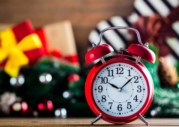 Alarm clock on wooden table with Christmas gifts — Stock Photo, Image