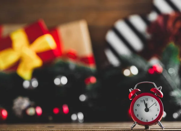 Alarm clock on wooden table with Christmas gifts — Stock Photo, Image