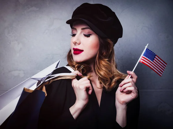 ショッピング バッグと灰色の背景にアメリカ合衆国の国旗の帽子スタイルの赤毛の女の子 — ストック写真