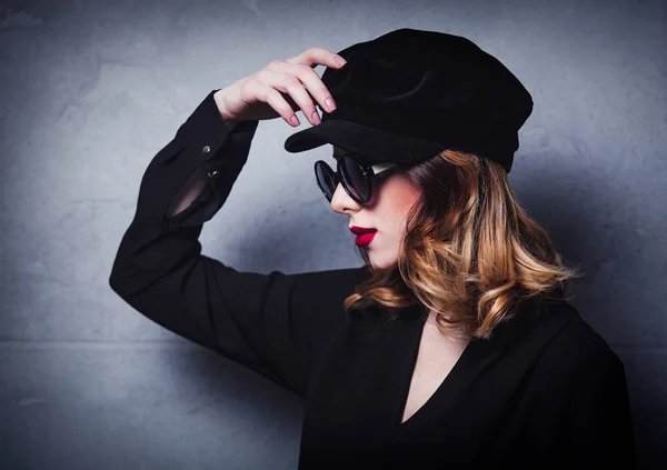 黒い帽子とサングラス グレーの背景の服でスタイル赤毛の女の子 — ストック写真