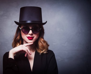 Silindir şapka ve güneş gözlüğü gri arka plan üzerinde stil ve gizemi Kızıl saçlı kız