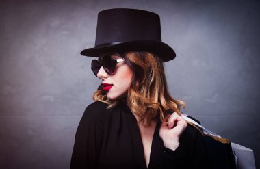 Tarzı Kızıl saçlı kız gri arka plan üzerinde alışveriş torbaları ile üst şapka