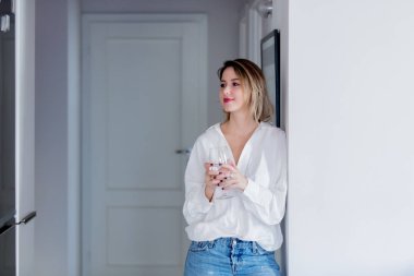 Genç kafkas kadın beyaz gömlek ve mavi jeans sonraki kadeh şarap ile duvar. 