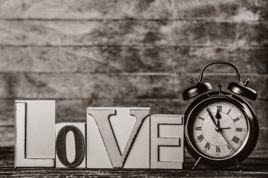 Çalar saat ve kelime üzerinde ahşap masa seviyorum. Görüntü siyah beyaz renk tarzı