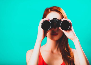 Yeşil arka plan üzerinde dürbün ile Kızıl saçlı kız.