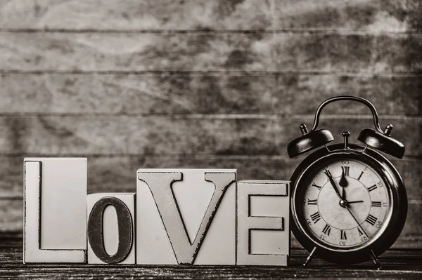 Çalar saat ve kelime üzerinde ahşap masa seviyorum. Görüntü siyah beyaz renk tarzı