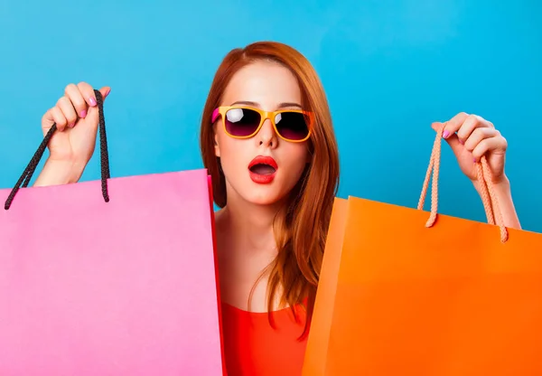 Mujer Pelirroja Sorprendida Sosteniendo Bolsas Compras Sobre Fondo Azul —  Fotos de Stock