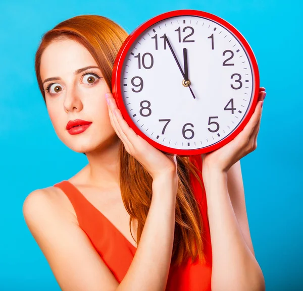 青色の背景に巨大な時計で赤毛の女の子 — ストック写真