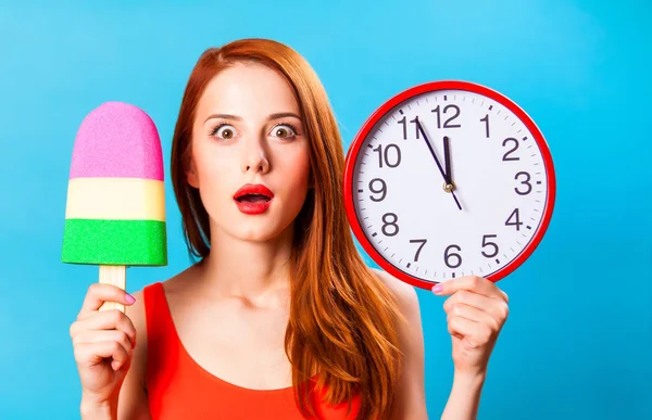 青い背景上の時計がグッズ アイス クリームと巨大な赤毛の女の子 — ストック写真