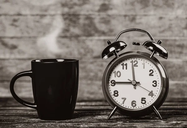 一杯のコーヒーと木製のテーブルの上の目覚まし時計 黒と白の色のイメージ — ストック写真