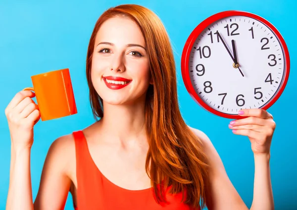 青い背景上の時計が紅茶のカップと巨大な赤毛の女の子 — ストック写真
