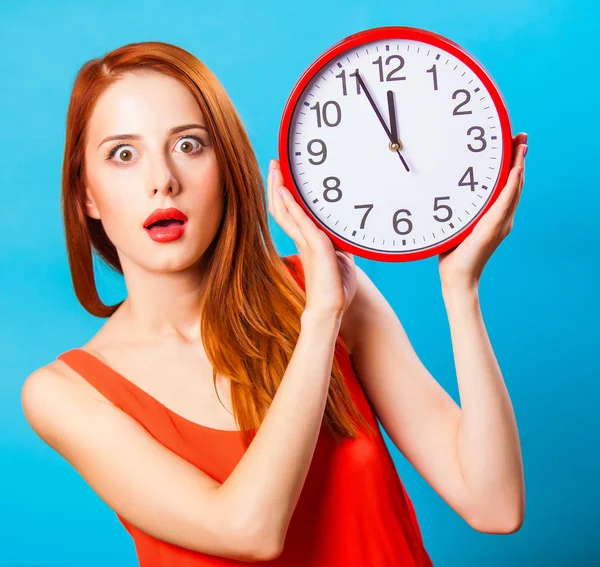 青色の背景に巨大な時計で赤毛の女の子 — ストック写真