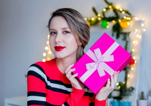 Belle femme en pull rouge tenant une boîte cadeau — Photo