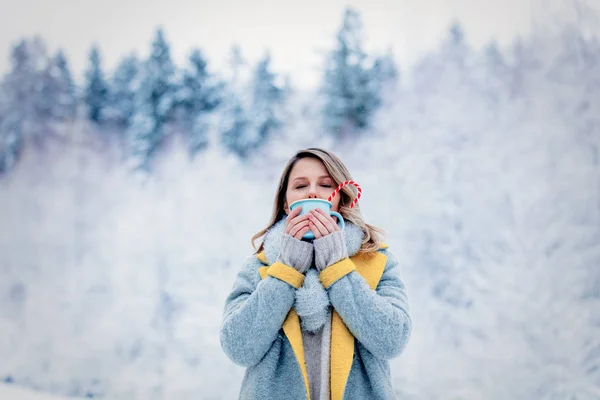 Dívka v šedém kabátě s cup v lese sněhu — Stock fotografie
