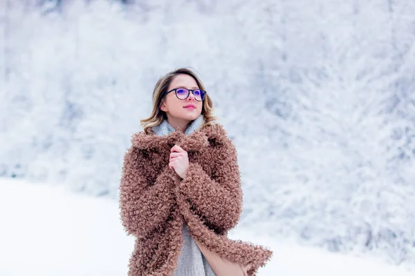 Krásná dívka v kabátě v lese sněhu — Stock fotografie