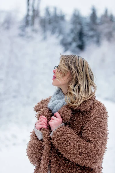 Krásná dívka v kabátě v lese sněhu — Stock fotografie