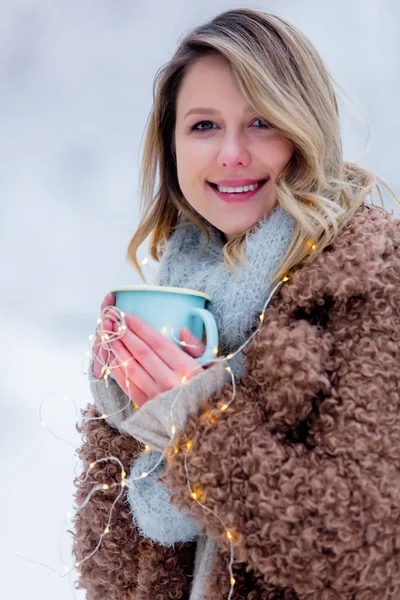 Menina de casaco com xícara de bebida em uma floresta de neve — Fotografia de Stock