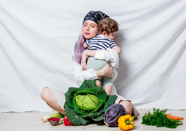Donna con un bambino seduto su un pavimento con verdura — Foto Stock
