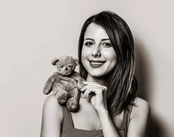 Meisje in een rode jurk met teddy bear speelgoed op schouder — Stockfoto