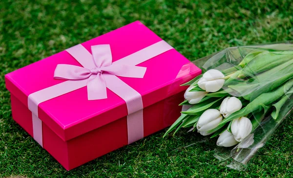 Boîte cadeau et tulipes sur pelouse d'herbe verte — Photo