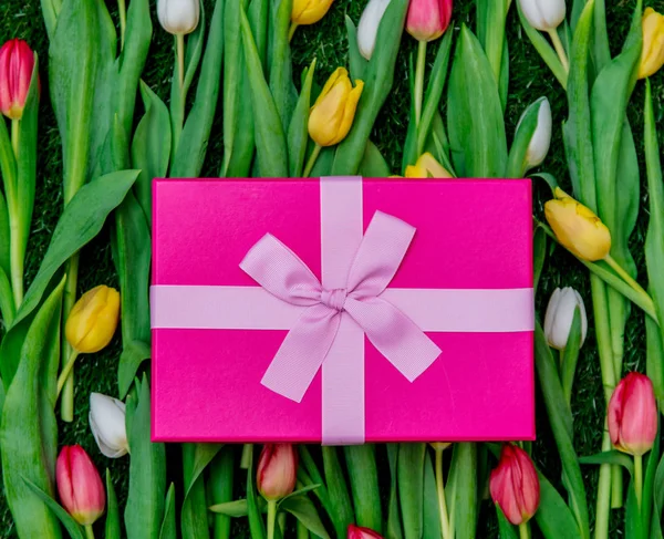 Caja de regalo y tulipanes en césped de hierba verde —  Fotos de Stock