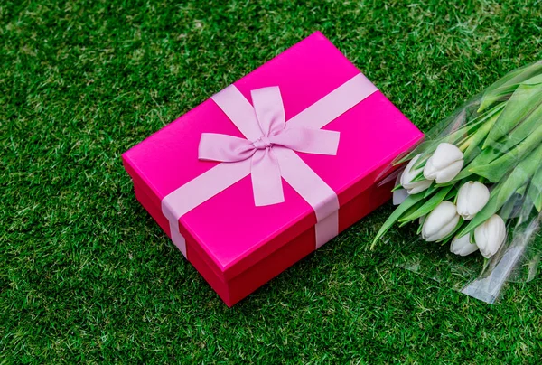 Boîte cadeau et tulipes sur pelouse d'herbe verte — Photo