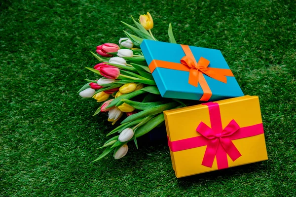 Cajas de regalo y tulipanes en césped de hierba verde —  Fotos de Stock