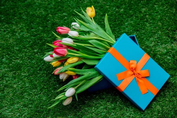 Boîte cadeau bleu et tulipes sur pelouse herbe verte — Photo