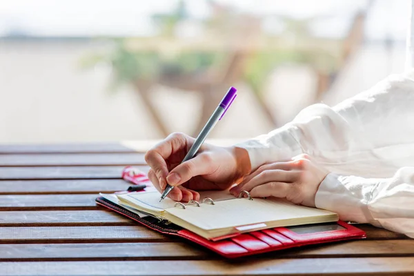 Hand med penna som skriver något i till en anteckningsbok — Stockfoto