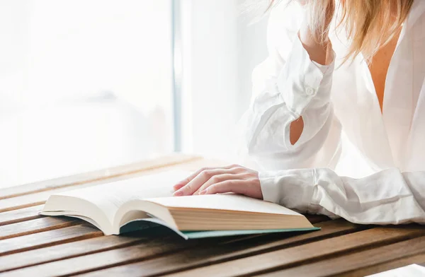 Жіночі руки з книгою на дерев'яному столі — стокове фото