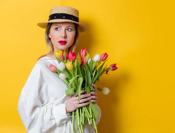 Mujer en camisa blanca y sombrero con tulipanes frescos de primavera — Foto de Stock