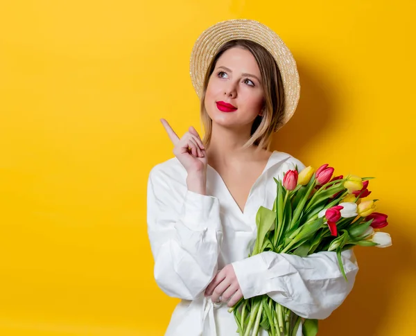 Mujer en camisa blanca y sombrero con tulipanes frescos de primavera — Foto de Stock