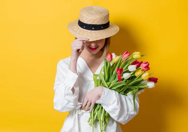 Kvinna i vit skjorta och hatt med färska våren tulpaner — Stockfoto