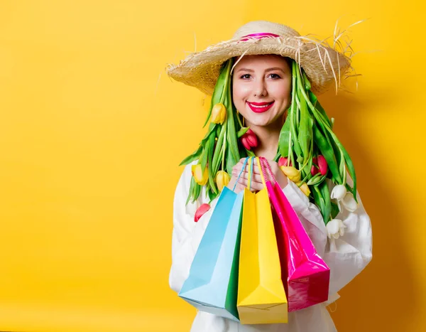 Donna in camicia bianca e cappello con tulipani freschi primaverili e shopping box — Foto Stock