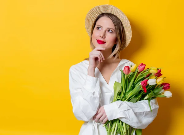 Mujer en camisa blanca y sombrero con tulipanes frescos de primavera — Foto de Stock