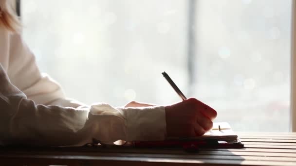Женщина пишет ручкой что-то в блокнот . — стоковое видео