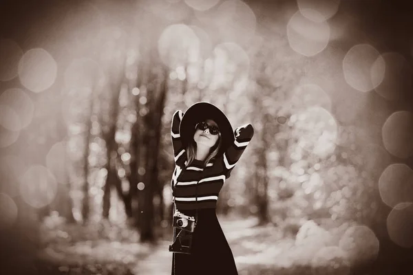 Girl in hat with a camera in autumn park — Stock Photo, Image