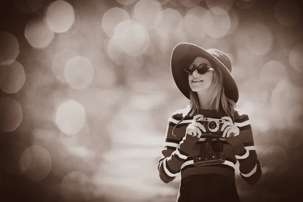 Chica en sombrero con una cámara en el parque de otoño — Foto de Stock