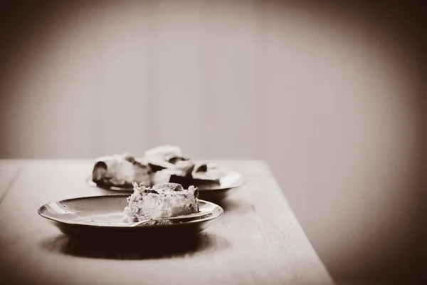 Plate with eaten cake and spoon on wooden table — Stock Photo, Image